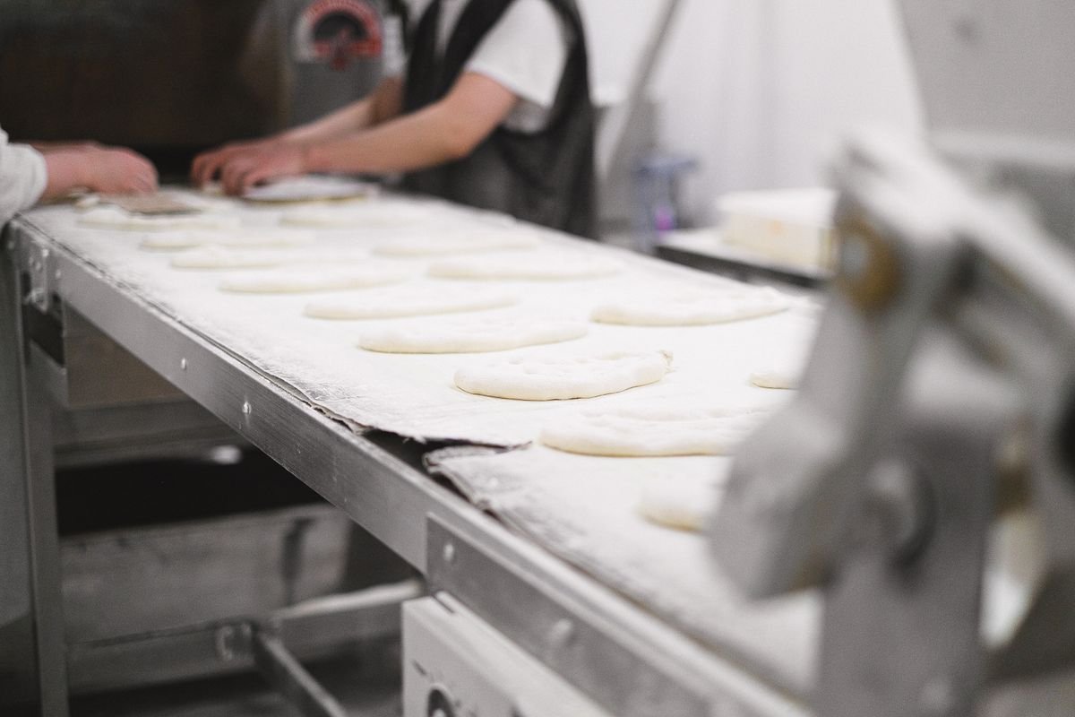 Bakery workers shaping dough on a production line