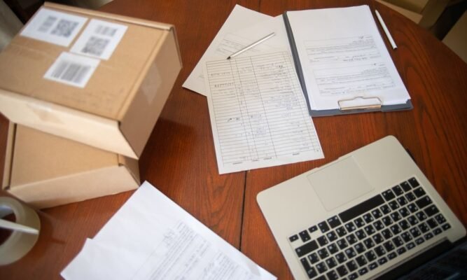 Shipping boxes and import paperwork on a desk - comparing trade license versus door-to-door import documentation