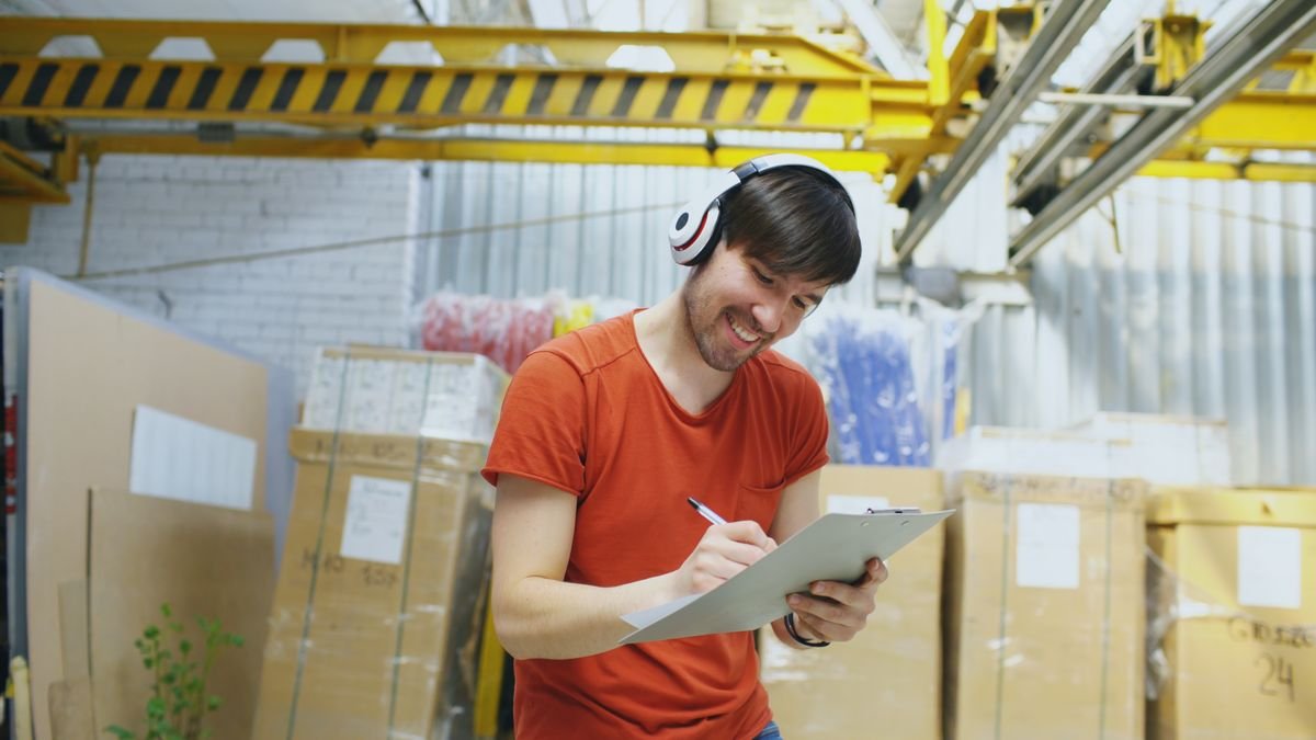 Quality inspector checking goods against a checklist in a factory warehouse