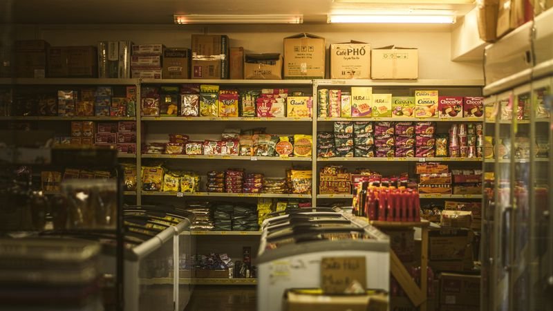 Small shop shelves stocked with snacks and chest freezers