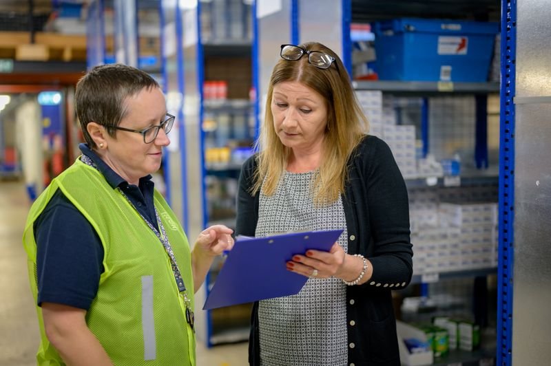 Two people reviewing an inventory checklist on a clipboard in a warehouse