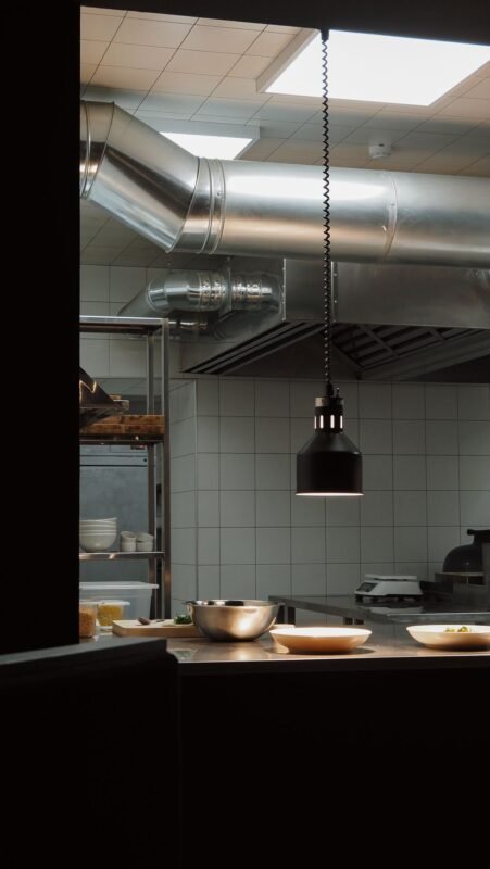 Empty commercial restaurant kitchen with stainless steel exhaust hood and fittings