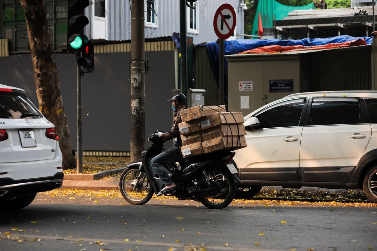 Delivery motorbike carrying stacked boxes through city traffic