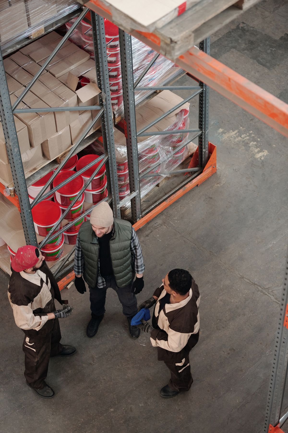 Warehouse staff discussing stock near pallet racking from above