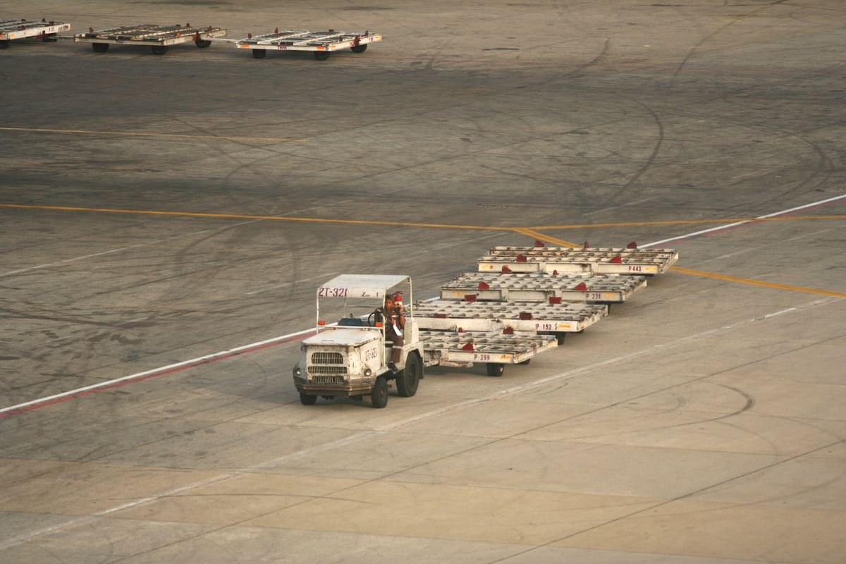 Ground handling cargo dollies being towed across an airport tarmac