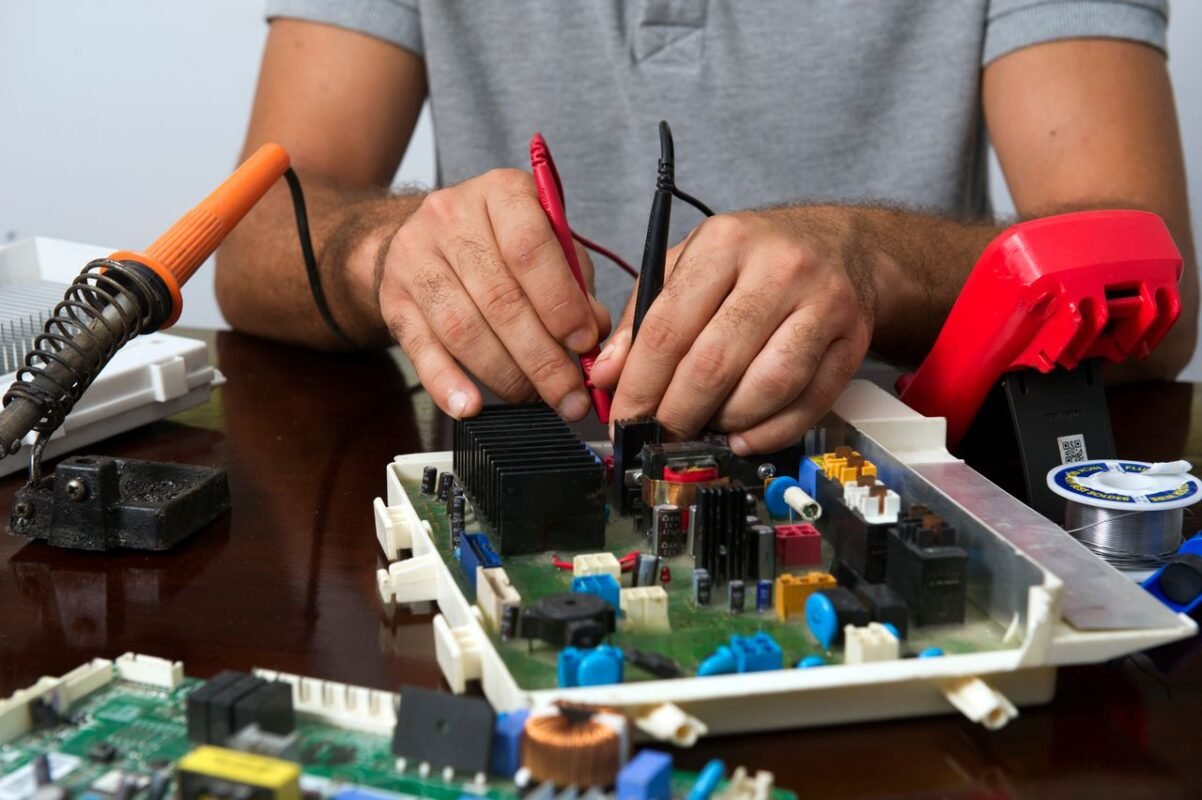 Technician using multimeter probes to test an electronic circuit board