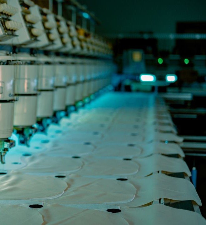 Row of industrial multi-head embroidery machine heads over fabric