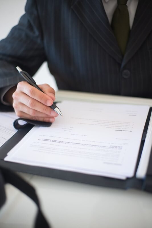 Businessperson signing a contract document in a folder