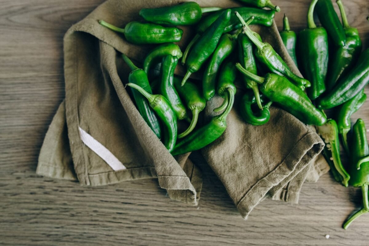Freshly harvested green chili peppers piled on a cloth on a wooden table
