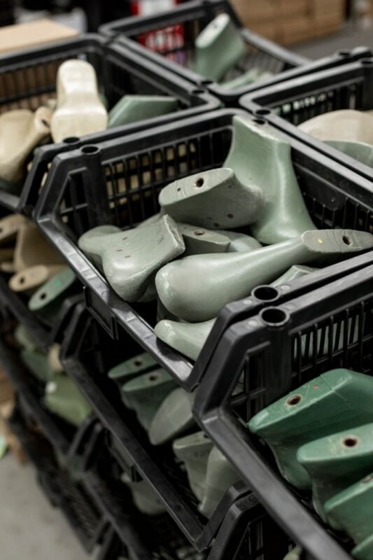 Shoe lasts stored in black plastic crates in a footwear workshop