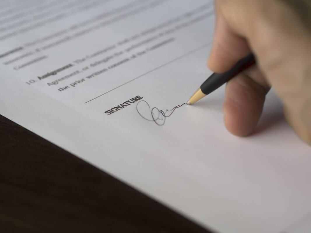 Hand signing a contract on the signature line