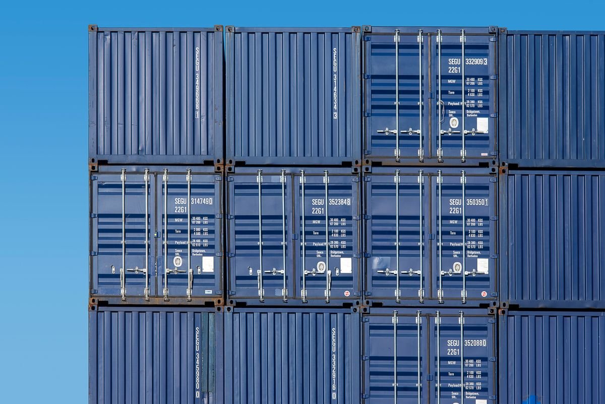 Stacked blue shipping containers at a port terminal