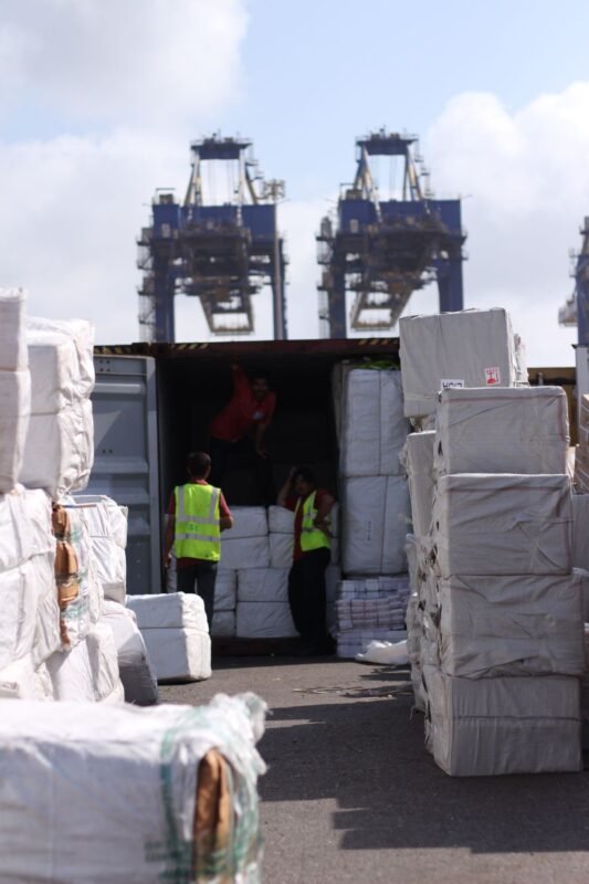 Workers loading export cargo into a shipping container at a port