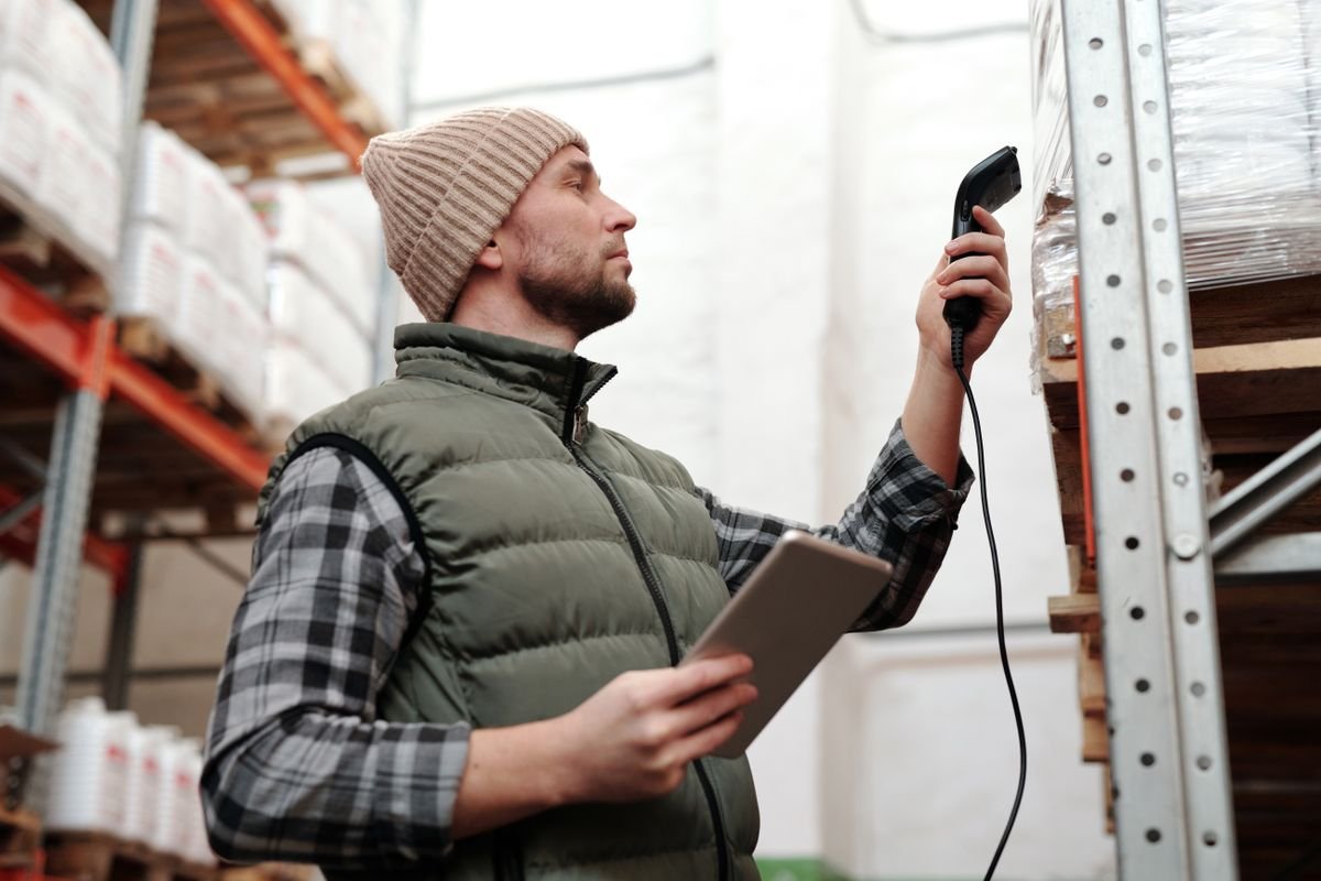 Warehouse worker scanning a pallet label with a handheld scanner and tablet