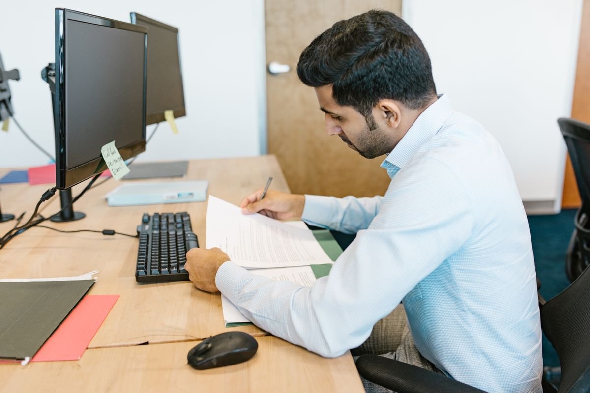 Office worker reviewing a printed declaration at a desk with a computer