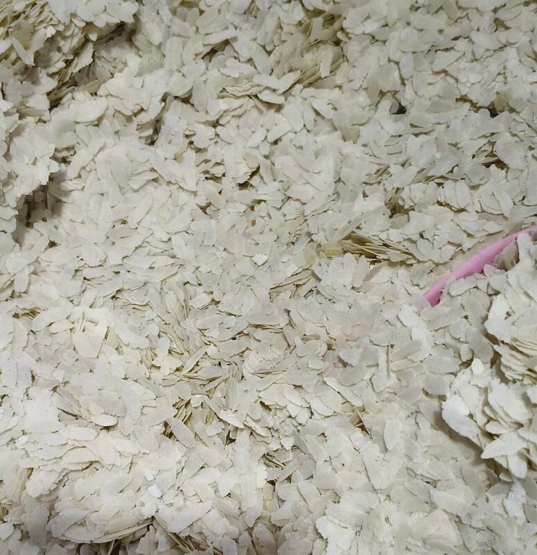 Close-up of a large heap of white flattened rice flakes (chira, poha) after processing