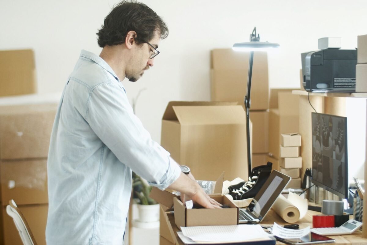 Small business owner packing imported products into cartons at a desk