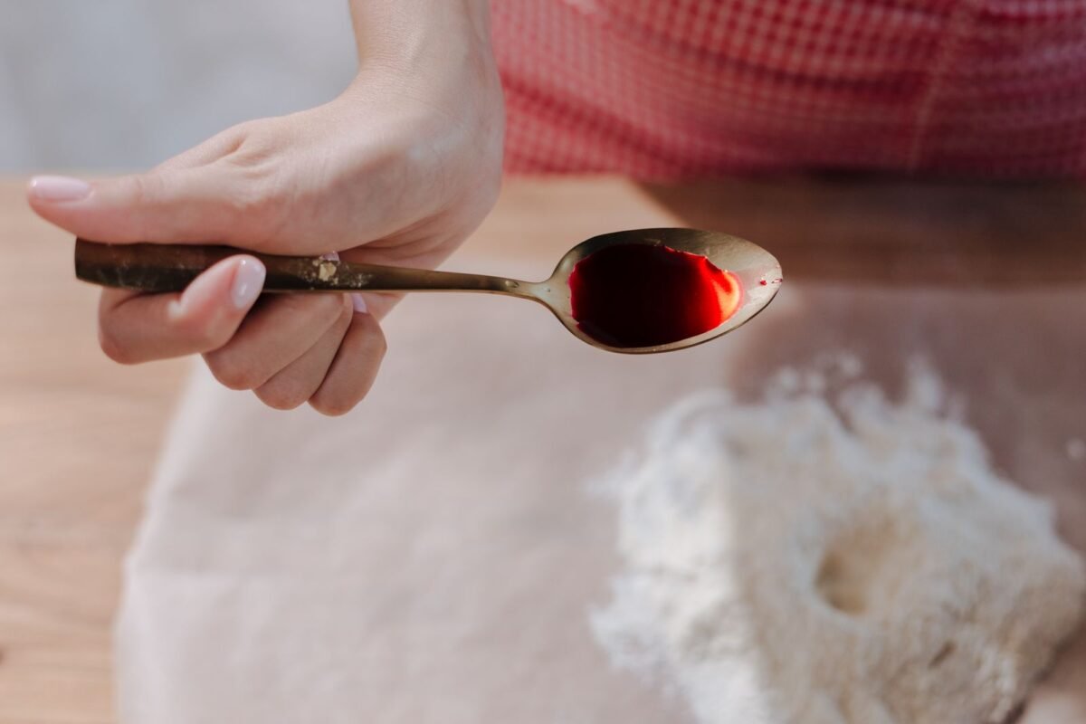 Spoon of liquid red food colour held over flour