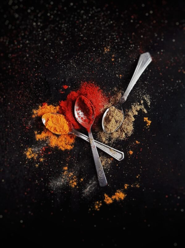Spoons of red, yellow and brown seasoning powders on a dark surface