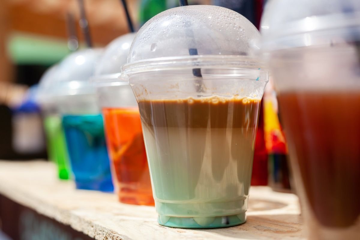 Iced tea and coloured cold drinks in disposable plastic cups at a stall