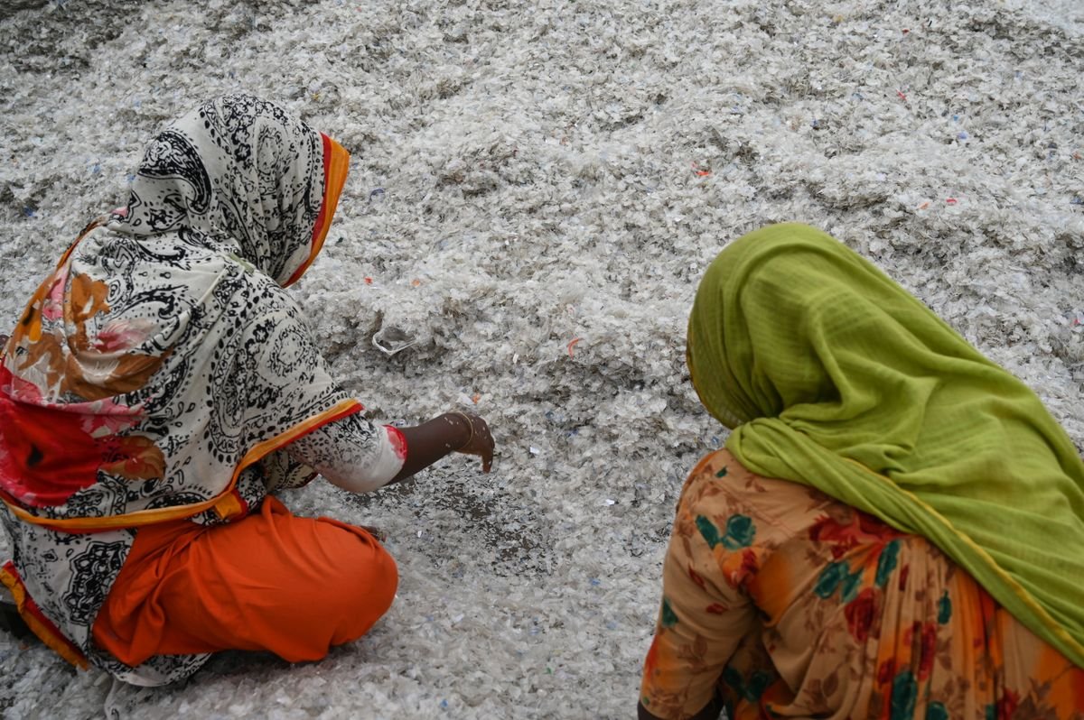 Women sorting shredded plastic bottle flakes at a recycling yard in Chattogram, Bangladesh