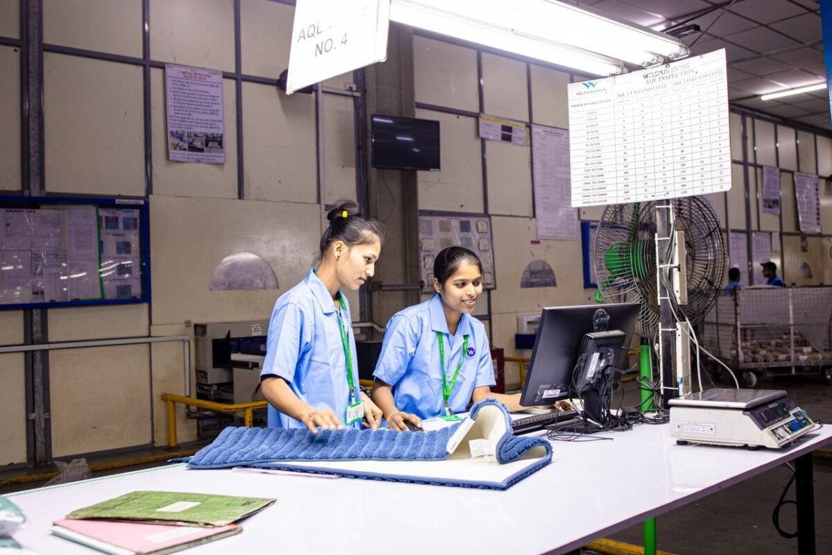 Two inspectors checking fabric at a factory inspection station during production
