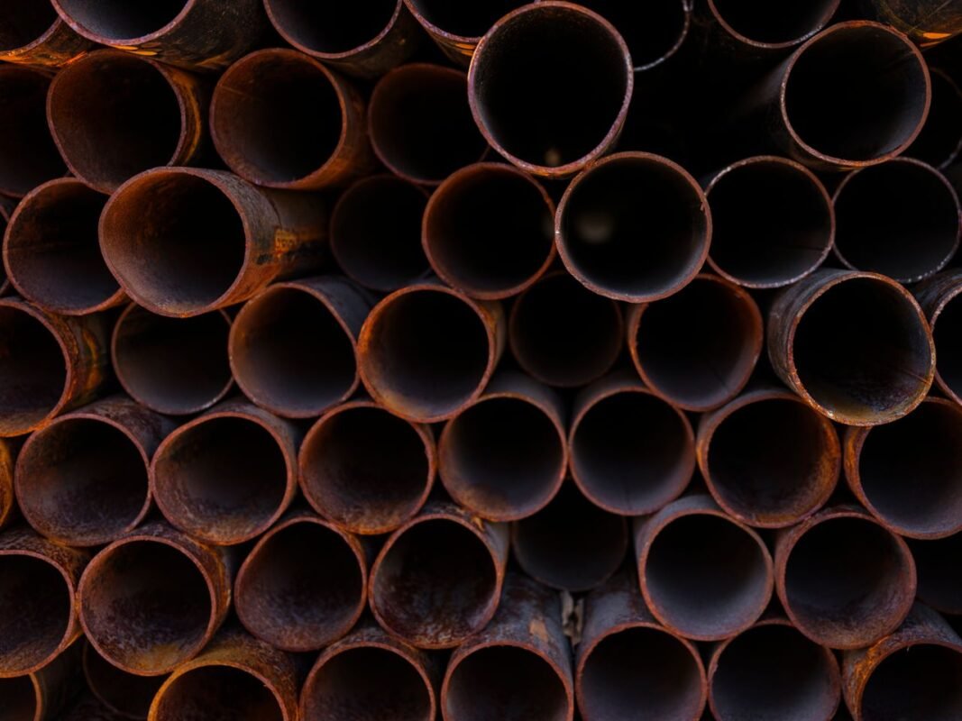 Stacked steel pipes showing surface rust from humid storage