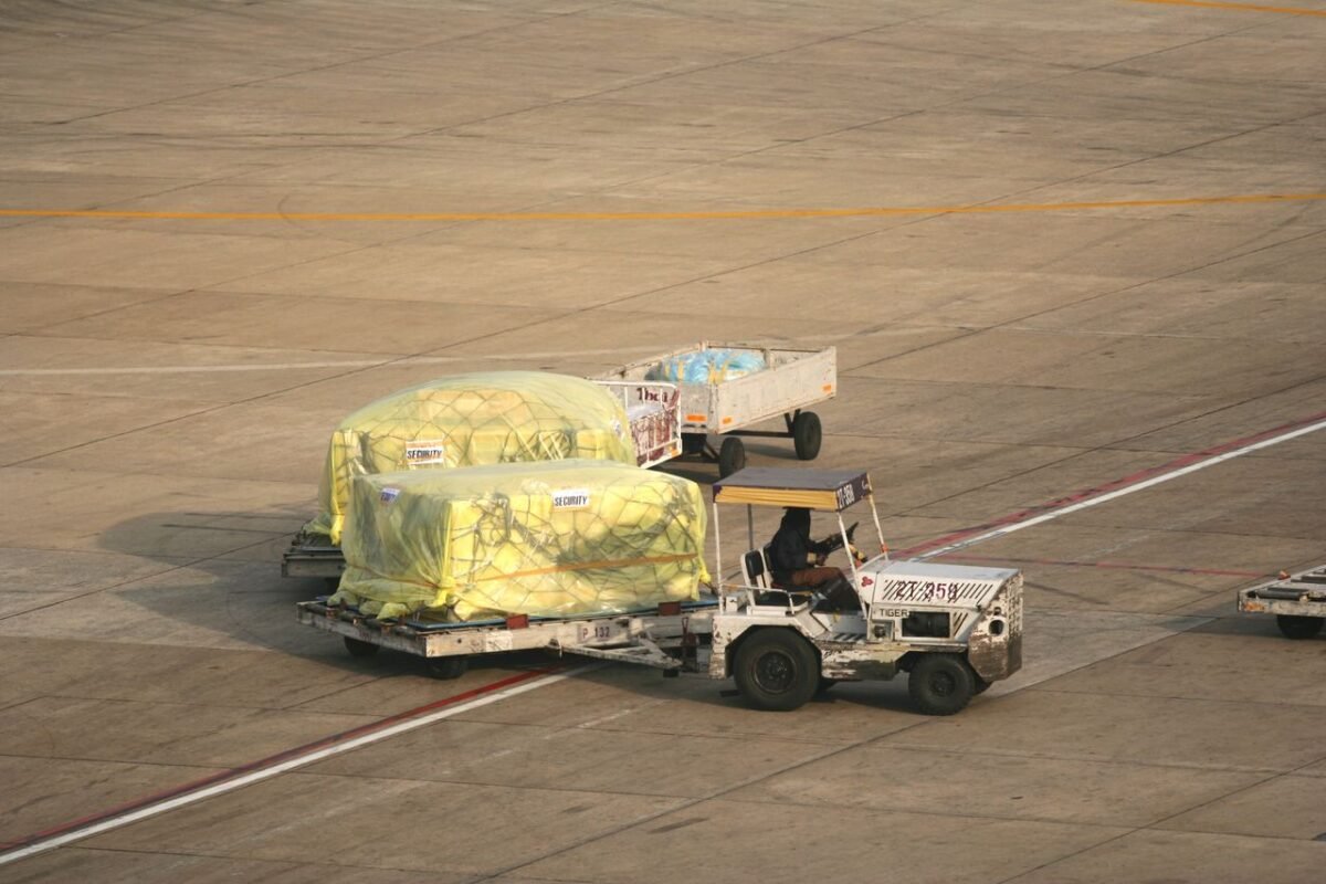 Covered air cargo pallets towed across an airport apron on dollies