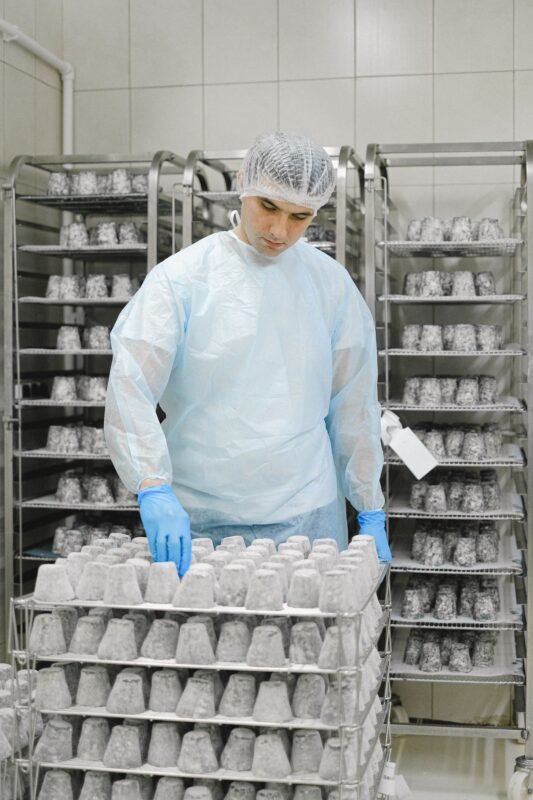 Food factory worker in hairnet and gloves checking products on racks