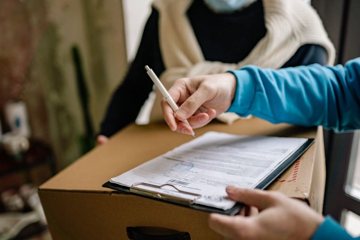 Consignee signing a delivery note on a carton