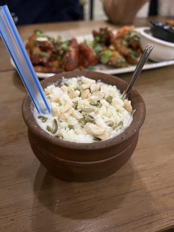 Thick white yogurt in a traditional clay pot topped with chopped cashews and seeds