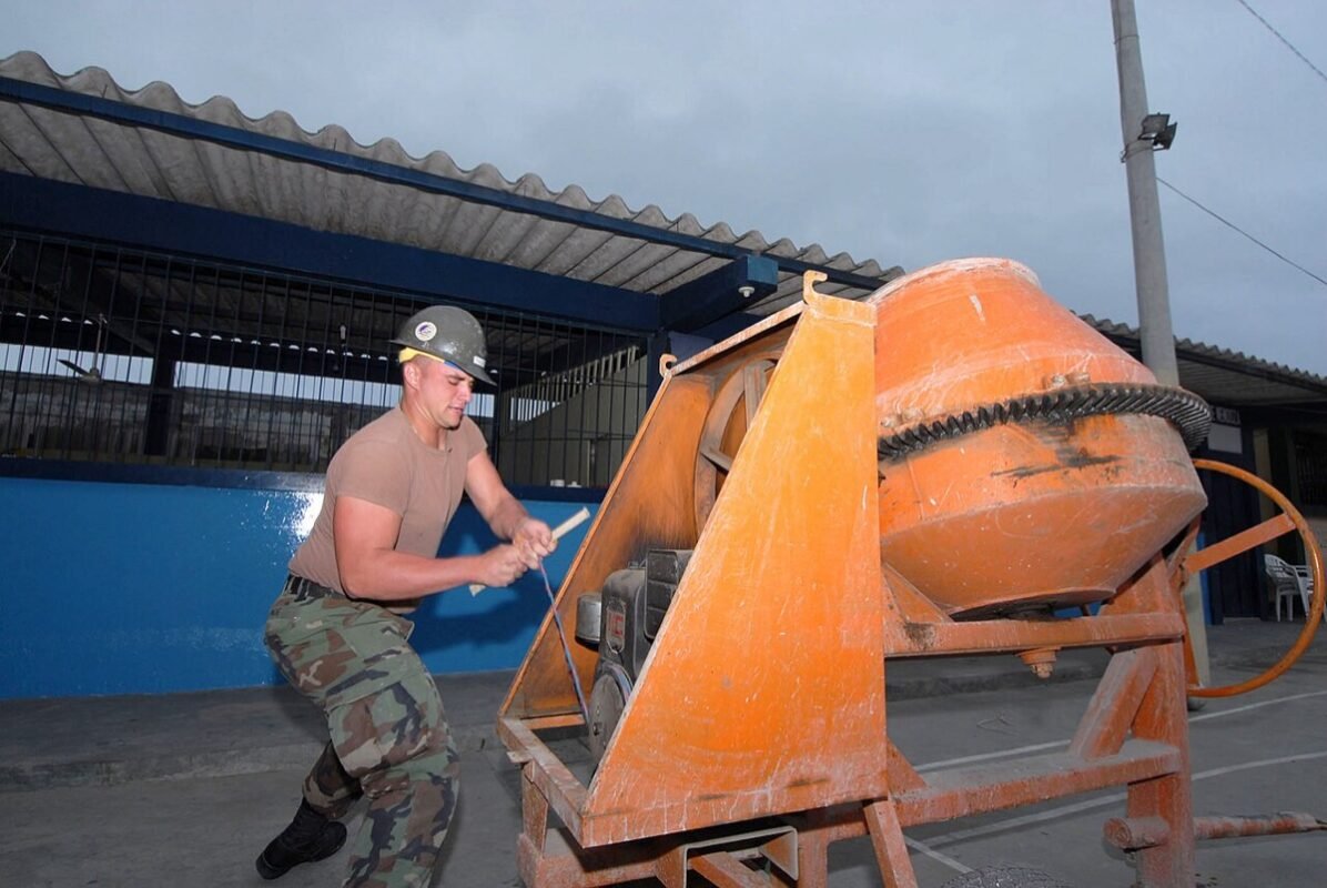 Operator starting a drum concrete mixer on a building site