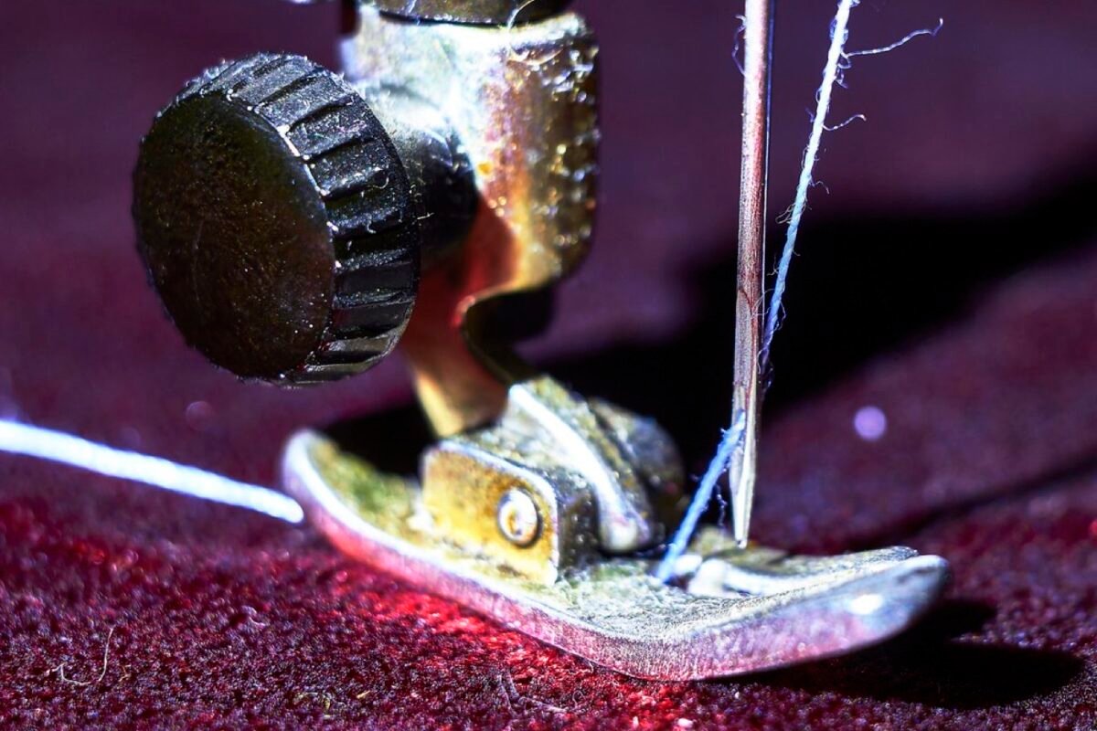 Close-up of a sewing machine needle and presser foot stitching fabric