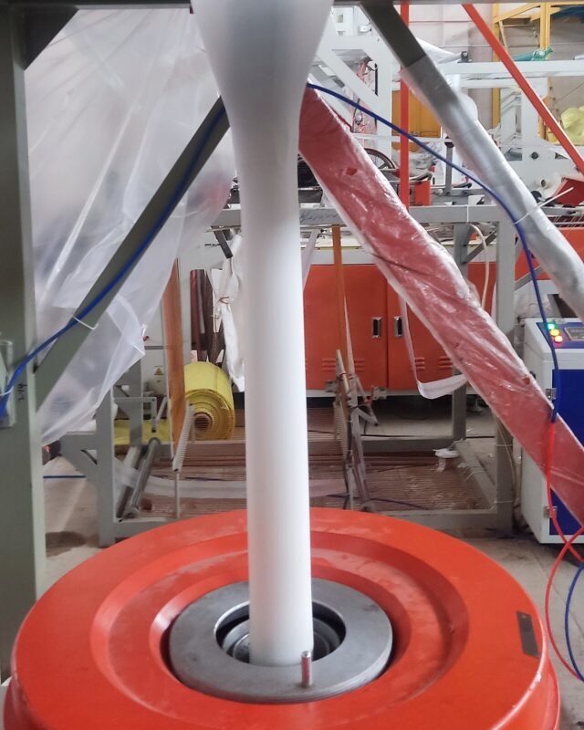 Blown film extrusion machine forming a polythene film tube at the die