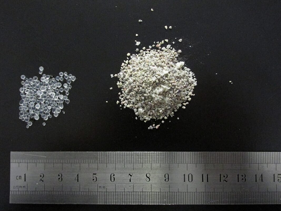 Silica gel beads and clay desiccant granules beside a ruler