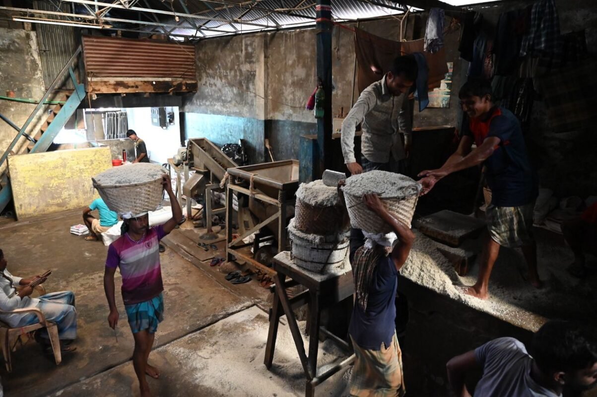 Workers carrying milled rice baskets in a small rice mill